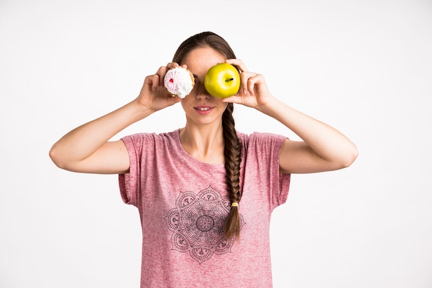 Photo gratuite femme couvrant son visage avec cupcake et pomme