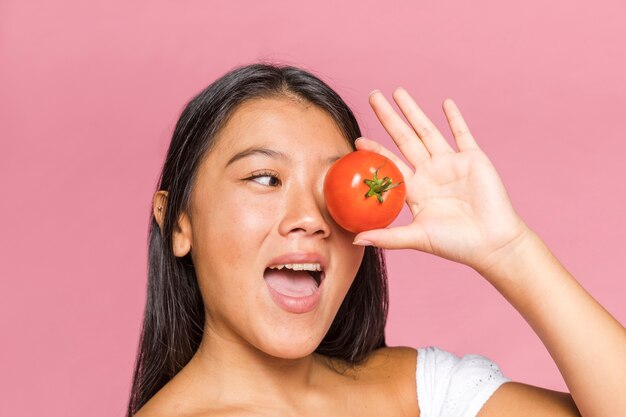 Femme, couvrir, oeil, tomate