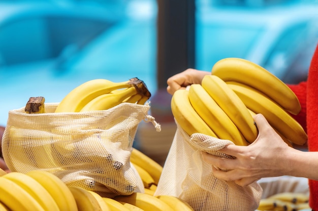 Photo gratuite femme cueillant des bananes dans un sac réutilisable ecologie thématiques du jour de la terre