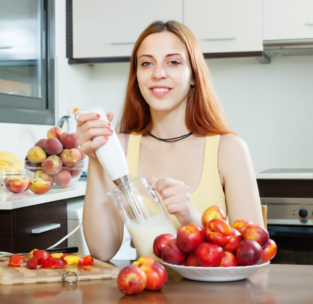 Femme cuisinant des boissons lactées avec des nectarines à la cuisine