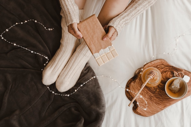 Photo gratuite femme de culture avec du chocolat près de miel et de thé