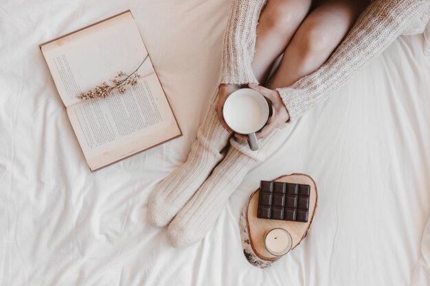 Femme de culture avec du lait près de livre et de chocolat