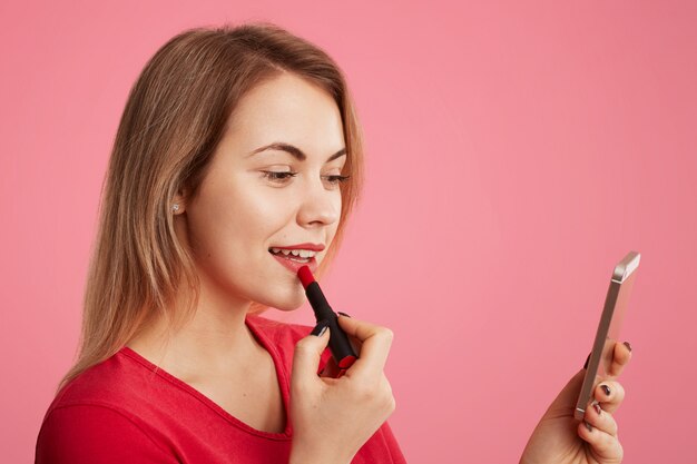 Femme dame peint des lèvres avec du rouge à lèvres rouge, utilise un téléphone intelligent comme miroir, se prépare à un rendez-vous avec un bel homme