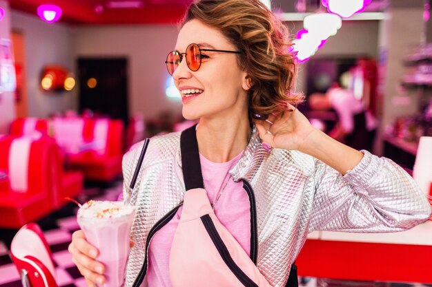 Femme dans un café américain rétro vintage des années 50 assis à table buvant un cocktail de milk-shake dans un style hipster