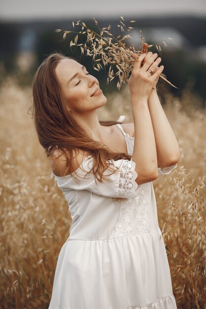 Femme dans un champ d'été. Brunette en robe blanche.