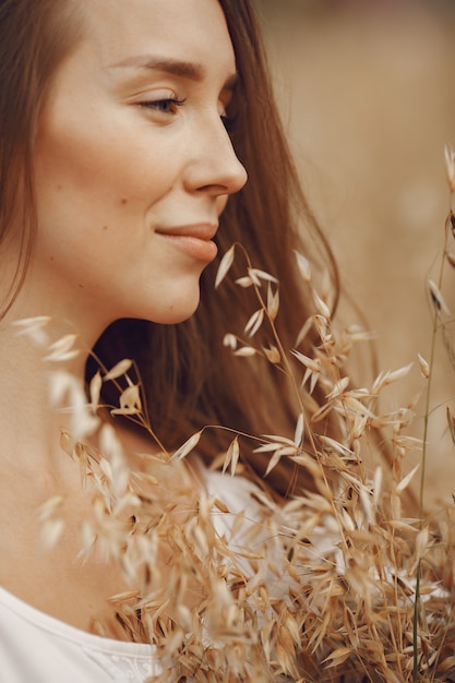 Femme dans un champ d'été. Brunette en robe blanche.