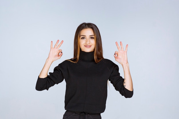 femme dans une chemise noire montrant un signe de plaisir.