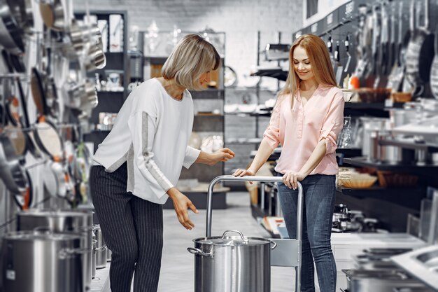 Femme dans un chemisier rose achète des plats dans le magasin