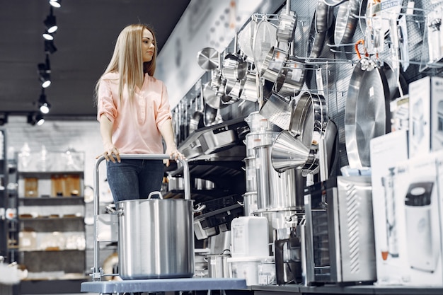 Femme dans un chemisier rose achète des plats dans le magasin