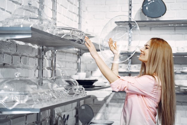 Femme dans un chemisier rose achète des plats dans le magasin