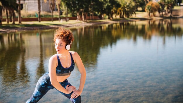 Femme dans les écouteurs, faire des exercices près de l&#39;eau