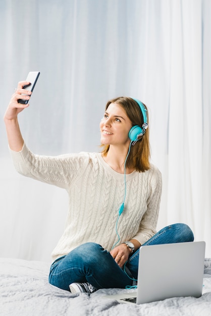 Femme dans les écouteurs prenant selfie