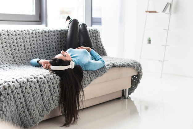 Photo gratuite femme dans les écouteurs reposant sur le canapé