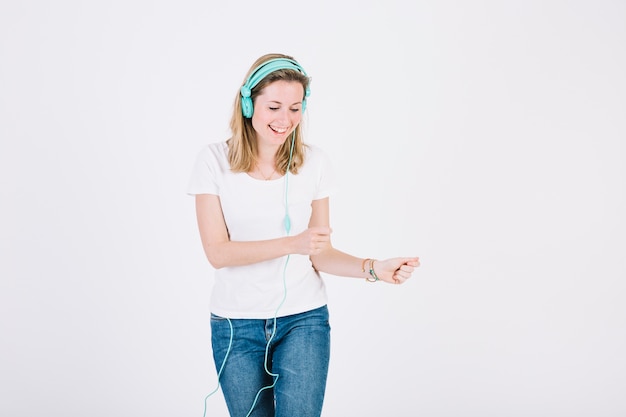 Femme dans les écouteurs en souriant et en dansant