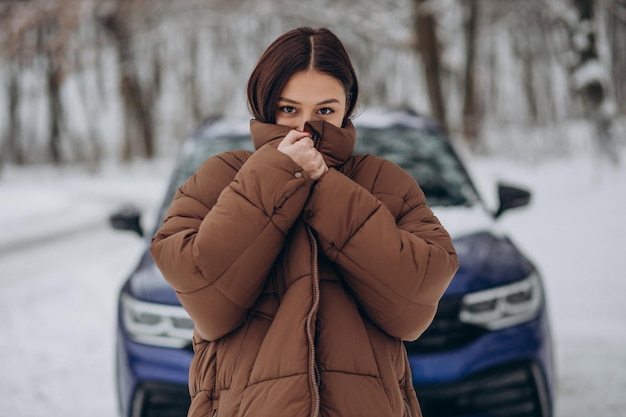 Femme dans la forêt d'hiver par sa voiture