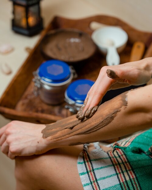 femme dans le hammam appliquant un masque de boue brune à ses bras