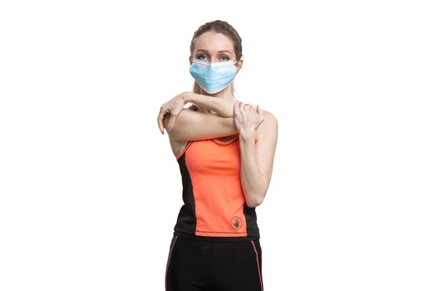 Femme dans un masque facial et costume de sport orange travaillant pendant la quarantaine
