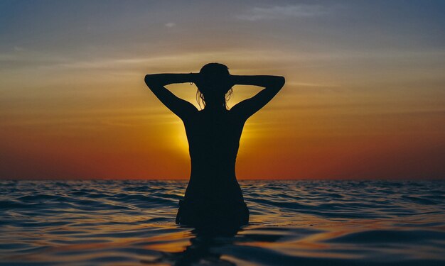 Femme dans l'océan au coucher du soleil