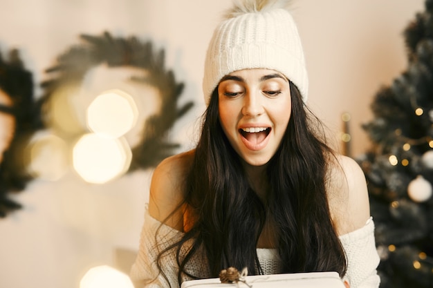 Femme dans un pull blanc. Dame avec des coffrets cadeaux. Notion de Noël.