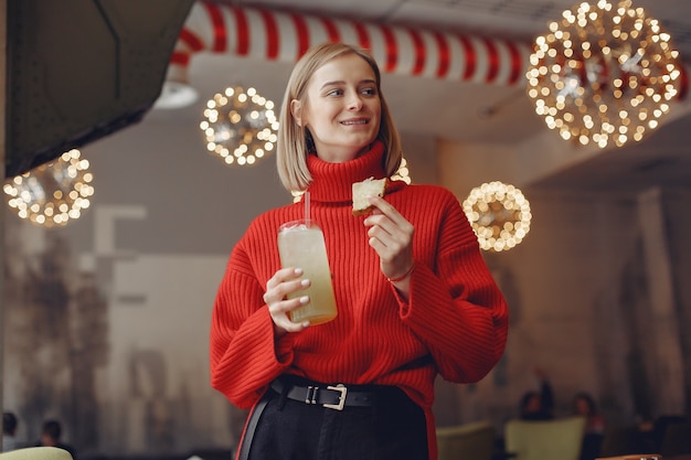 Femme dans un pull rouge. Lady boit un cocktail.