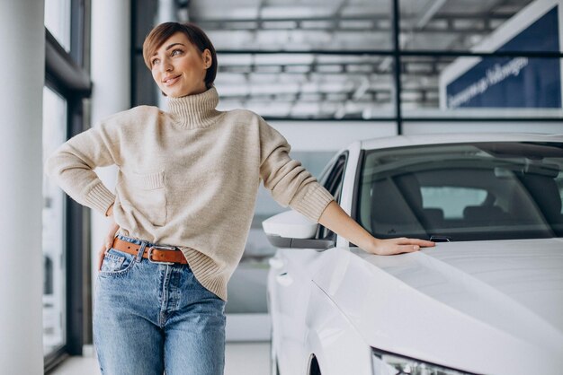 Femme dans une salle d'exposition de voiture choisissant une nouvelle voiture