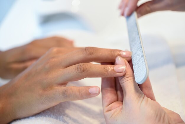 Femme dans un salon de manucure recevant une manucure avec une lime à ongles