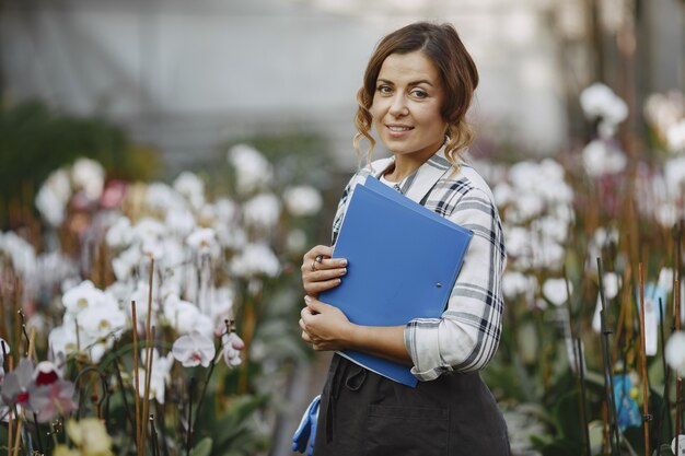 Femme dans une serre. Un ouvrier vérifie des fleurs. Fille avec dossier