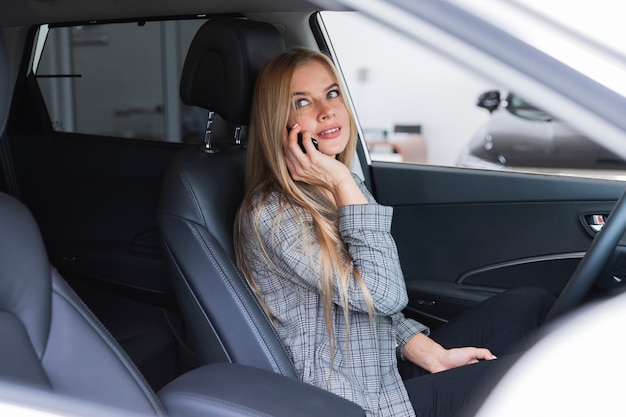 Femme dans le siège du conducteur parle au téléphone