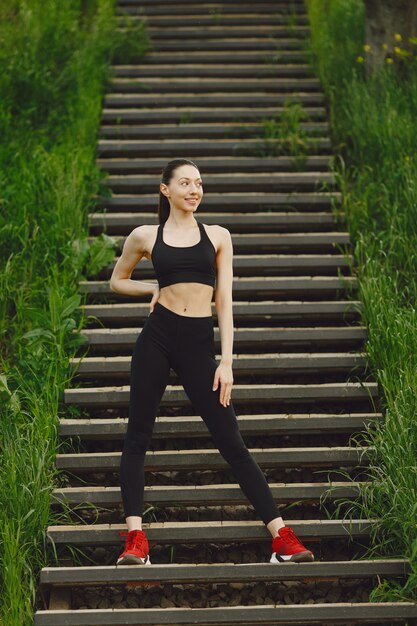 Femme dans un spoerswear noir debout sur un escalier