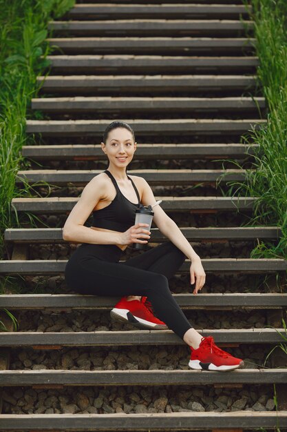 Femme dans un spoerswear noir debout sur un escalier