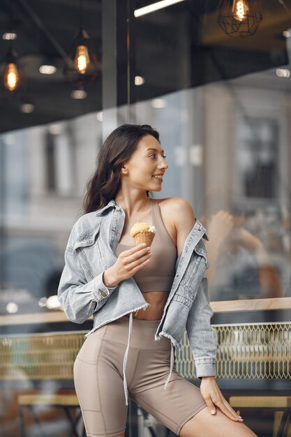 Femme dans une ville d'été. Dame à la crème glacée. Brunette près du bâtiment.