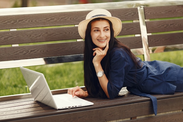 Femme dans une ville de printemps. Dame avec un ordinateur portable. Fille assise sur un banc.