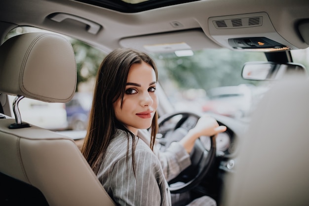 Photo gratuite une femme dans une voiture à l'intérieur garde la roue tourner en souriant en regardant les passagers à l'arrière de l'idée d'un chauffeur de taxi parlant à un compagnon de police qui demande des directions pour conduire l'examen des documents.