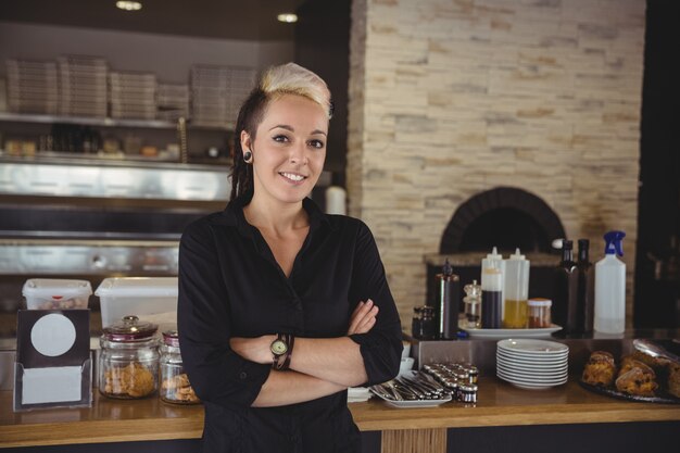 Femme debout avec les bras croisés dans la cuisine