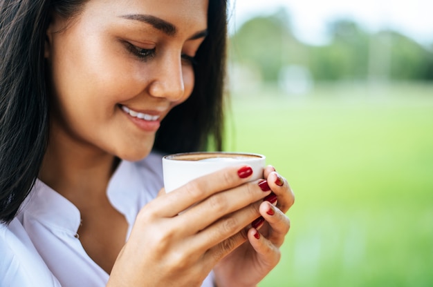 Photo gratuite femme debout, buvant du café sur le pré