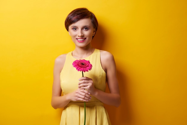 Femme debout devant la caméra avec une fleur