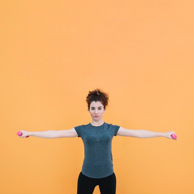 Femme debout et exercer avec des haltères