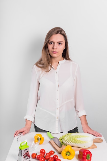 Femme debout avec des légumes sur la table