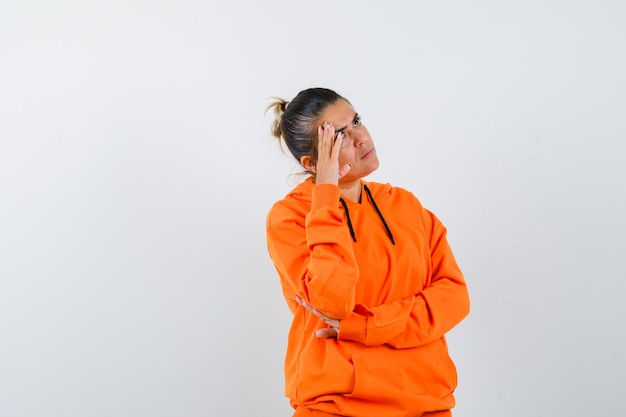 Femme debout en pensant pose en sweat à capuche orange et à l'accent