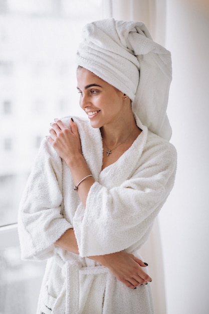 Photo gratuite femme debout près de la fenêtre en peignoir