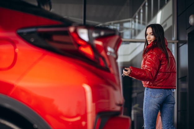 Femme debout près de sa nouvelle voiture rouge