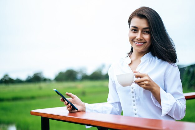 Femme debout sur un smartphone et tenant une tasse de café