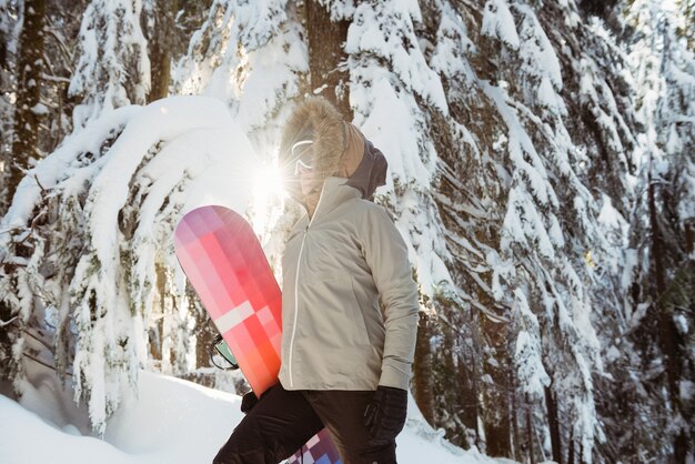 Femme debout et tenant un snowboard