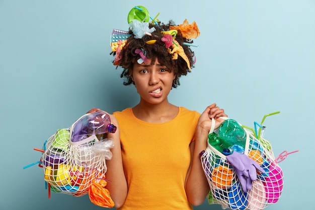 Femme avec des déchets plastiques dans un sac en filet