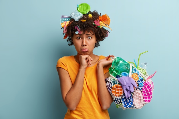 Femme avec des déchets plastiques dans un sac en filet