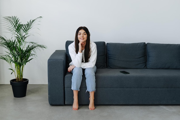 Photo gratuite une femme décontractée heureuse parle au téléphone assise sur un canapé à la maison