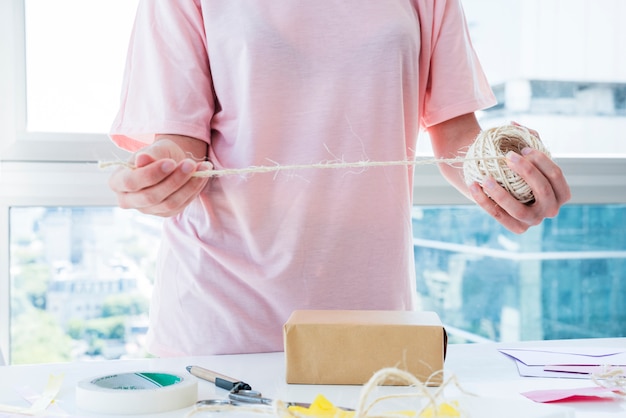 Femme décorant la boîte avec du fil sur table