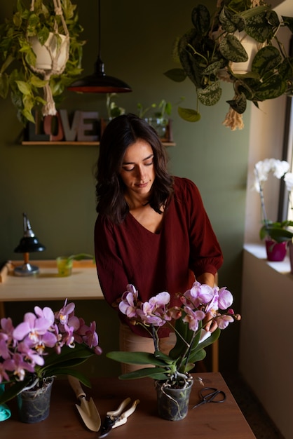 Photo gratuite une femme décore sa maison d'orchidées.