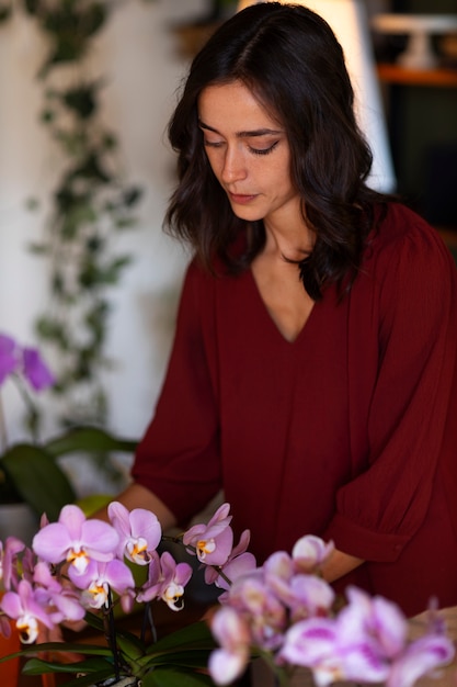 Une femme décore sa maison d'orchidées.