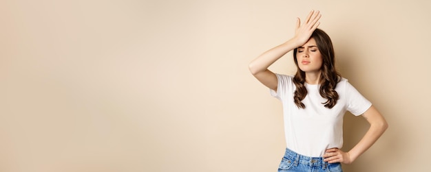 Photo gratuite femme déçue réagissant à l'échec gifler le front facepalm avec un visage triste sur fond beige